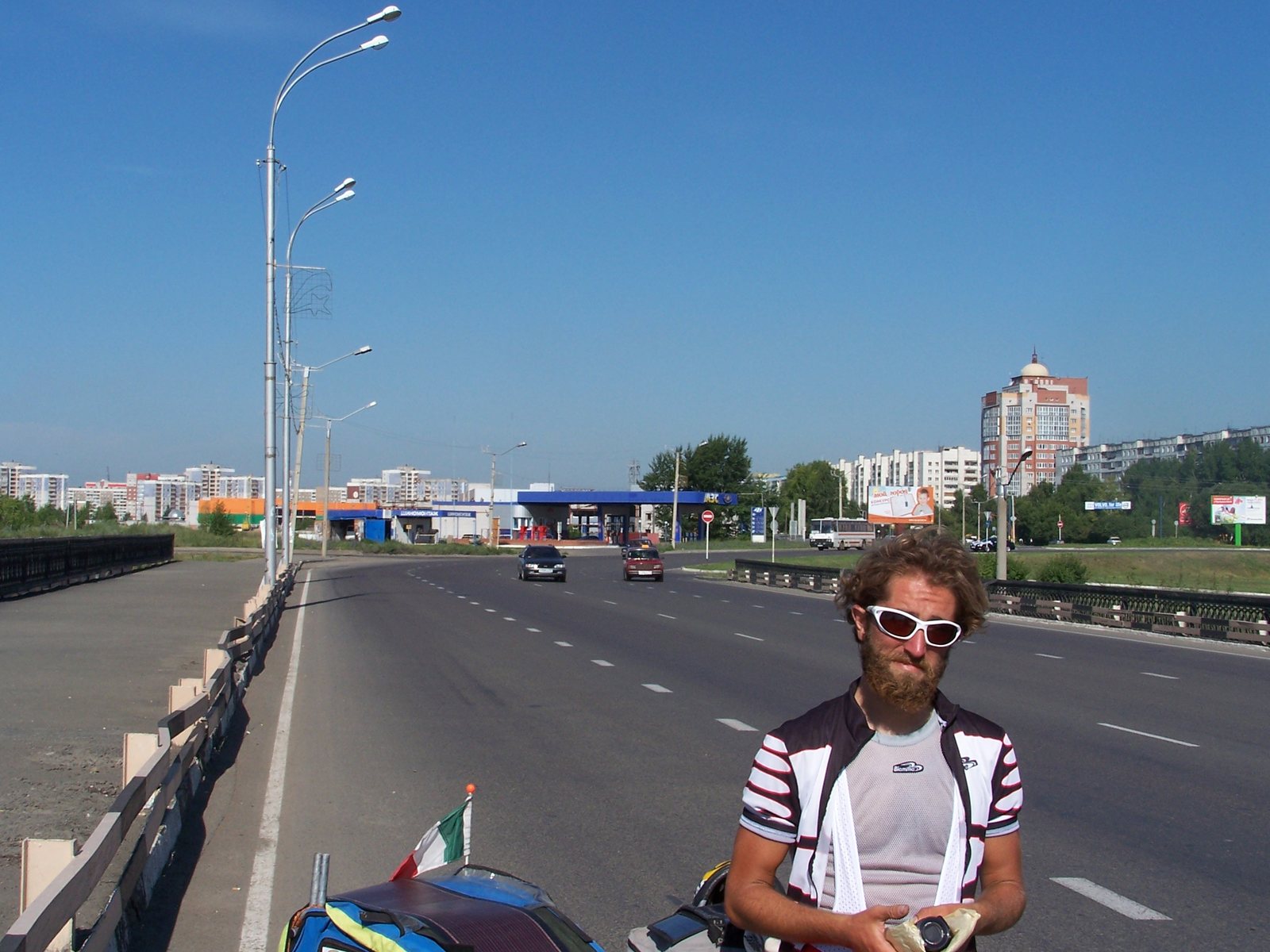 Ciclista in sosta su un ponte cittadino, con il pannello solare montato sul carrellino